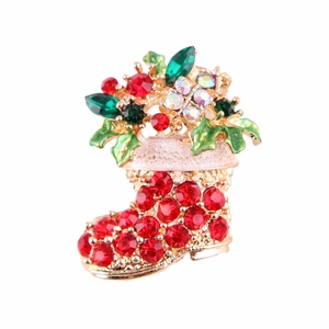 Detalle de broche de calcetín navideño con diamantes rojos y base dorada fina