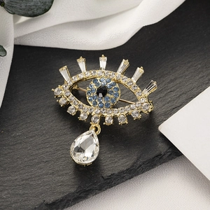 Broche Œil maléfique avec strass bleus et goutte de cristal sur une surface en pierre