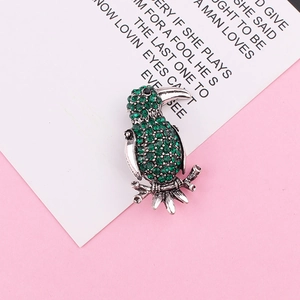 Detailed view of parrot brooch with green rhinestones and black gem eye on silver base