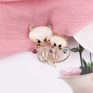 Détail de broches chats entrelacées avec pierres œil-de-chat et strass multicolores