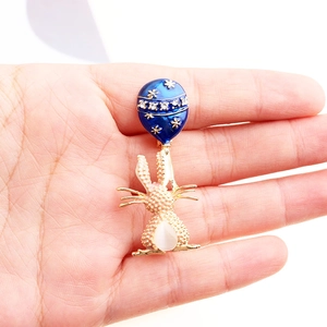 Dettaglio della spilla a palloncino in smalto blu con coniglio dorato e gemma bianca