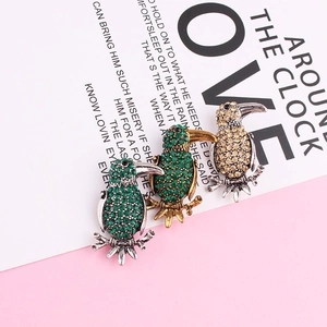 Detailed view of three crystal-encrusted toucan bird brooches in green and champagne colors