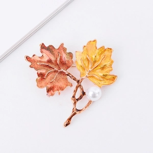 Close-up of enamel maple leaf brooch with red-yellow gradient and pearl accent