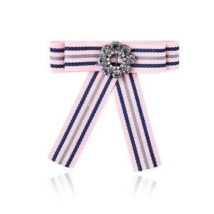 Macro detail of a pink ribbon bow brooch with navy stripes and a central crystal rhinestone