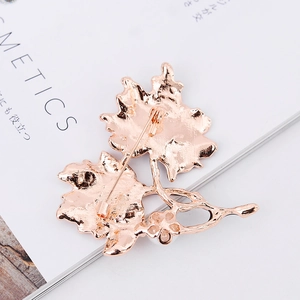 Back view of a rose gold maple leaf brooch with detailed metal texture and safety pin