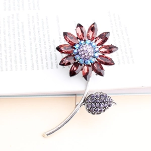 Floral pin brooch with dark red petal crystals and blue center on a vintage book