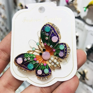 Dettaglio di una spilla a farfalla in smalto colorato con strass brillanti incastonati