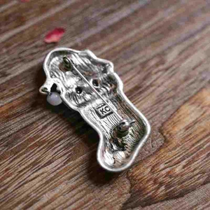Vintage silver Christmas cat brooch with hanging pearl on a rustic wooden background
