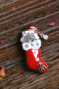 Detail of Christmas cat brooch in festive red sock on elegant dark wood background