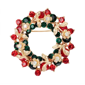Detalle de broche de corona navideña con pedrería roja y verde sobre base dorada