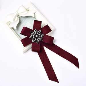 Detail of wine red bow brooch with snowflake rhinestone and elegant ribbon texture