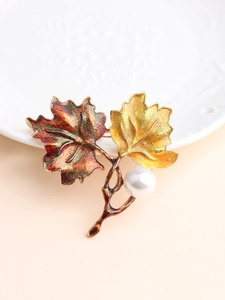 Macro view of maple leaf brooch with enamel gradient finish and large faux pearl