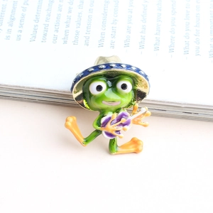 Funny green frog enamel pin wearing a blue hat and holding flowers on a book background