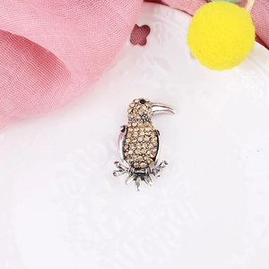 Vintage bird brooch with champagne crystals on an ornate white decorative plate