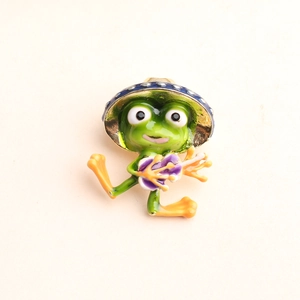 Detail of green enamel frog brooch with a blue polka dot hat playing a purple guitar
