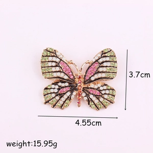 Broche papillon colorée avec cristaux roses et verts dans une monture dorée