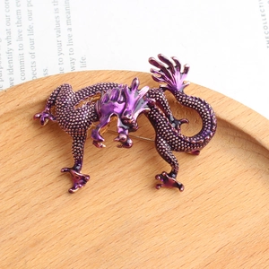 Vue macro d'une broche dragon en émail violet avec écailles sur support en bois