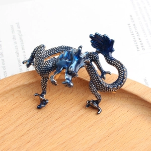 Vue macro d'une broche dragon en émail bleu sur un plateau en bois rustique