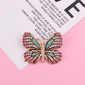 Détail d'une broche papillon dorée ornée de strass roses et bleus étincelants