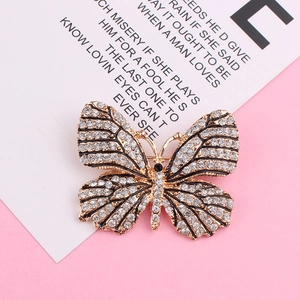 Détail d'une broche papillon dorée ornée de cristaux scintillants et d'émail noir