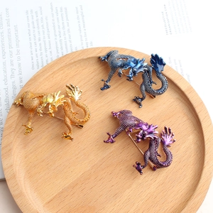 Broches dragon exquises en émail or bleu et violet sur un plateau en bois