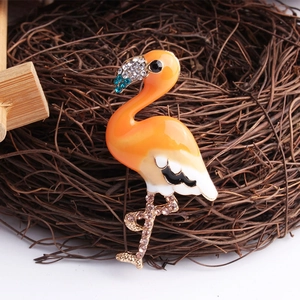 Detailed view of flamingo brooch with orange enamel and crystals in a bird nest