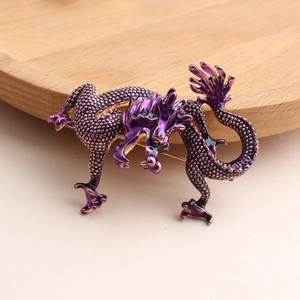 Gros plan d'une broche dragon violette avec écailles et finitions en émail doré