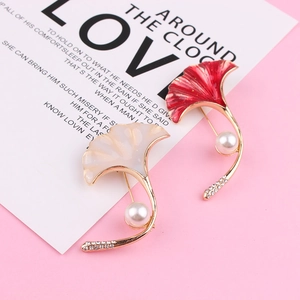 Close-up of enamel ginkgo leaf brooches with large pearls and sparkling rhinestones