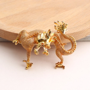 Vue macro de la broche dragon dorée avec écailles texturées et finition métallique polie