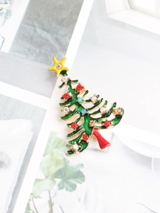 Détail macro d'une broche sapin de noël en émail avec strass colorés et étoile dorée