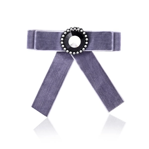 Detail of purple velvet bow brooch featuring a central black gemstone and crystal trim