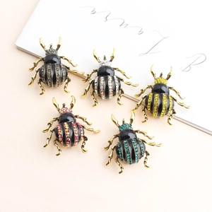 Retro rhinestone beetle brooches in five colors on a vintage cream pedestal