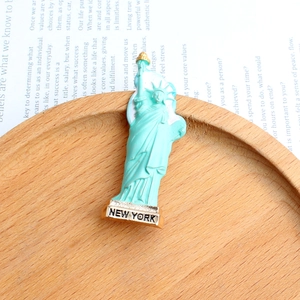 Close-up of Statue of Liberty brooch with New York text on golden base and mint enamel