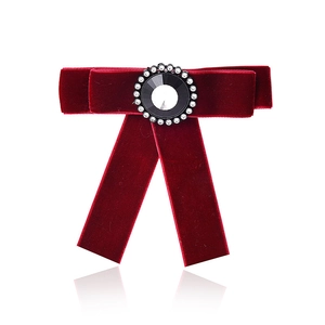 Close-up of a burgundy velvet bow brooch with a black gemstone and crystal trim