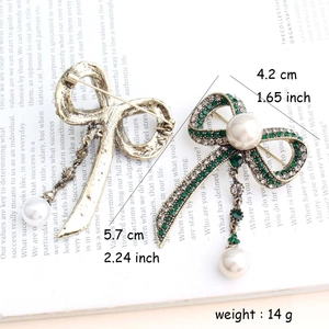 Vintage gold bow brooch with green rhinestones and white pearls on magazine background