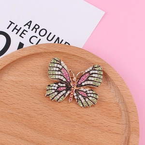 Gros plan détaillé d'une broche papillon avec strass roses et verts sur bois