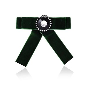 Detailed macro view of luxury dark green velvet bow brooch with sparkling crystal center