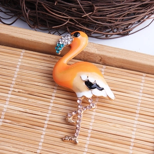 Exquisite flamingo brooch with orange enamel and sparkling rhinestones on bamboo background