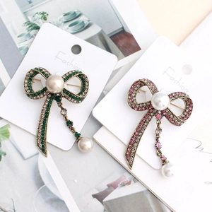 Close-up of vintage bow brooch with pearls, tassels, and intricate pavé rhinestone detailing