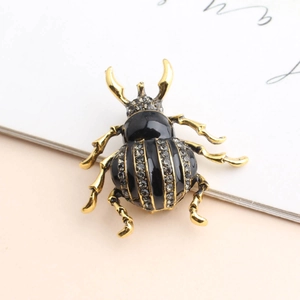 Macro shot of beetle brooch with black enamel inlay and white rhinestones on gold alloy