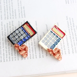 Macro detail of calculator brooches with blue enamel buttons and bronze coin accents