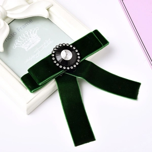 Elegant emerald green velvet bow brooch with central black gemstone and crystal halo