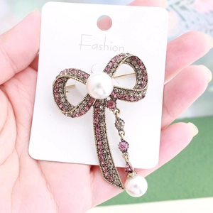Detail of vintage bow brooch with pink crystals and elegant white pearl pendant