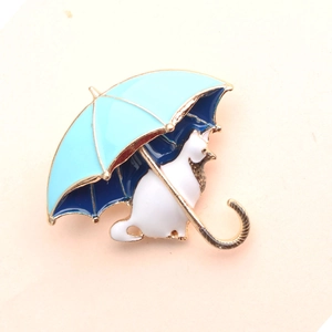 Dettaglio della spilla in smalto con gatto bianco sotto un ombrello blu scuro
