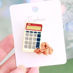 Calculator and gold coins enamel brooch pin on a white fashion display card