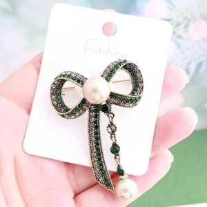 Retro gold bow brooch with emerald rhinestones and dangling white pearls on card