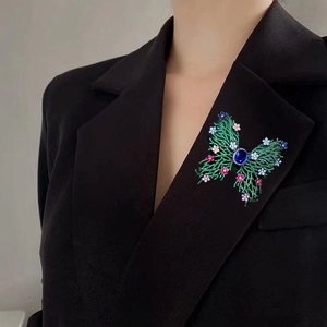 Macro view of butterfly brooch with green micro-pave crystals on a black suit jacket