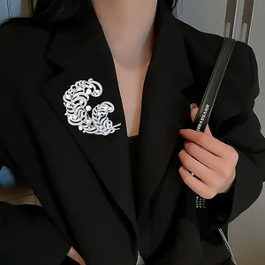 Close-up of double feather brooch with pearls and zircon on a black blazer lapel