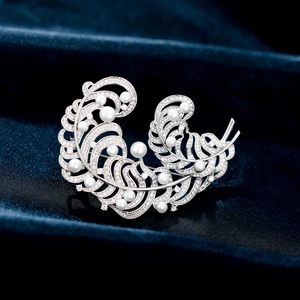 Macro detail of silver double feather brooch with cubic zirconia and fresh water pearls