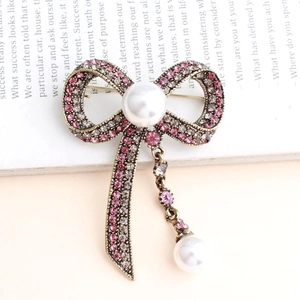 Vintage bow brooch with pink crystals and pearls on a retro background